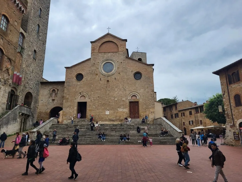 Façade en pierre et larges marches animées sur la piazza de San Gimignano