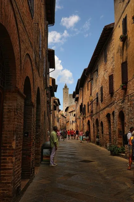Rue pavée de San Gimignano bordée de maisons médiévales et touristes