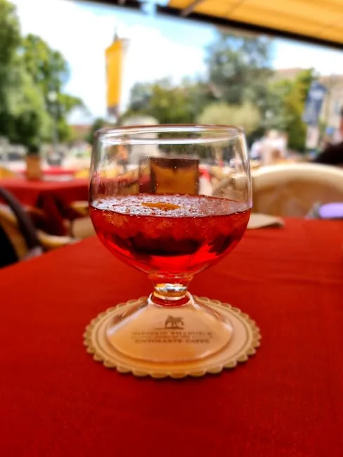 Verre d'apéritif rouge posé sur nappe rouge en terrasse à San Gimignano