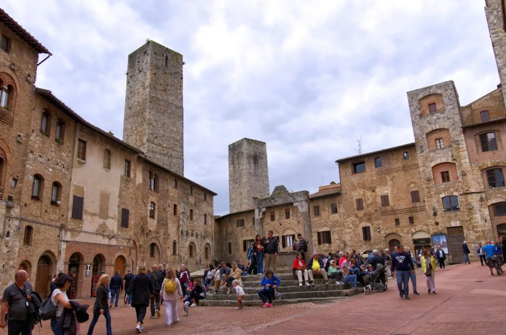 Place centrale de San Gimignano avec tours médiévales et visiteurs