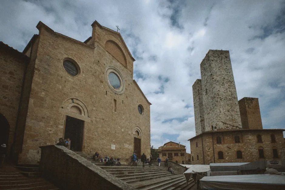 Façade d'une église avec marches et tours médiévales à San Gimignano
