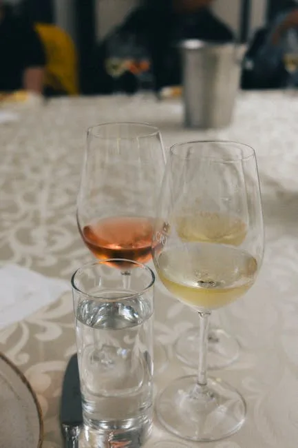 Deux verres de vin (blanc et rosé) et verre d'eau sur table.