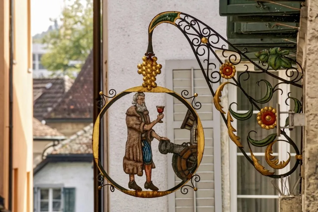 Smeedijzeren uithangbord in San Gimignano met een man die een glas vasthoudt
