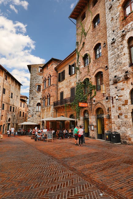 Cobblestone square in San Gimignano with outdoor café and historic buildings