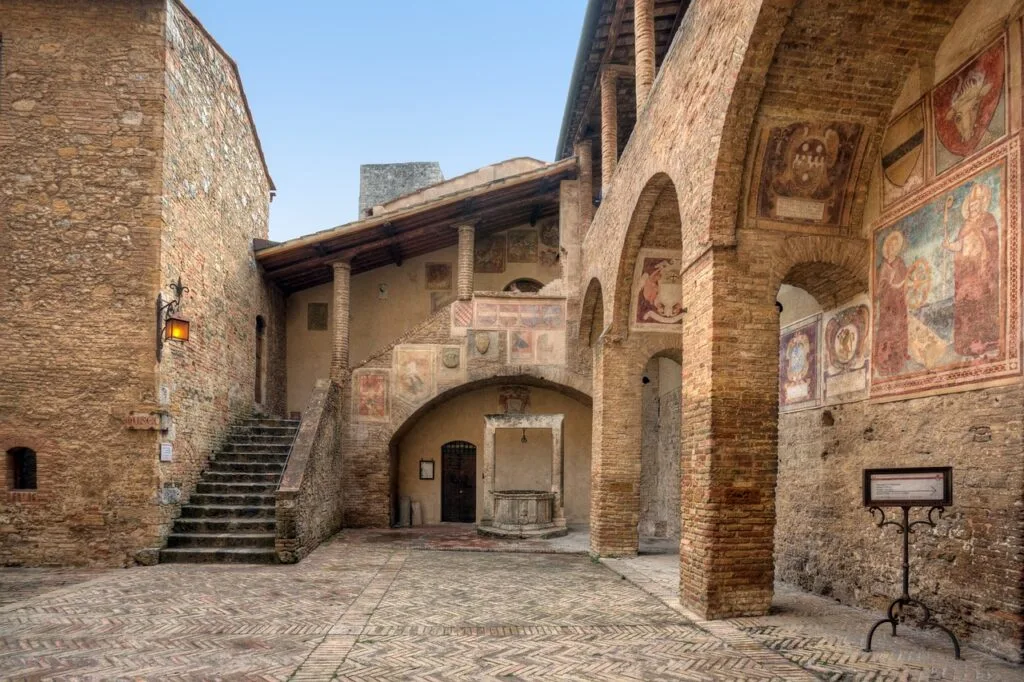 Binnenhof met bakstenen bogen en middeleeuwse fresco's in San Gimignano