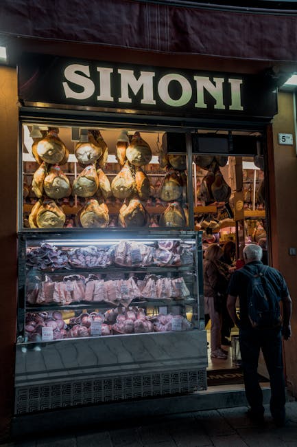 Shopkeeper slicing prosciutto behind the salumeria counter in San Gimignano