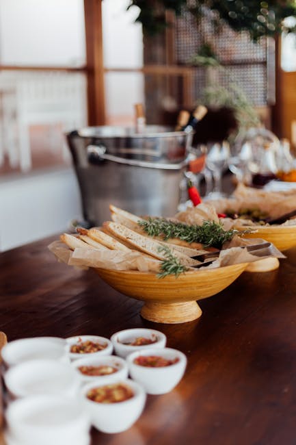 Brett mit Brot, frischen Kräutern und Schälchen mit Gewürzen auf einem Holztisch