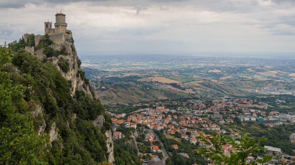 Medieval cliffside fortress overlooking a sprawling valley and town below