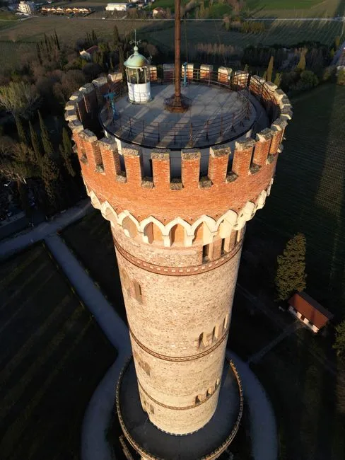 Tall cylindrical medieval tower with crenellations overlooking San Gimignano countryside
