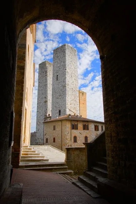 Stone arch frames San Gimignano's characteristic soaring medieval towers against sky