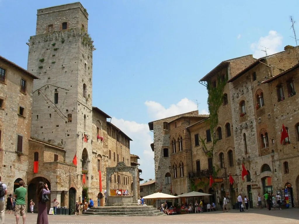 Crowded San Gimignano square with medieval tower and central fountain