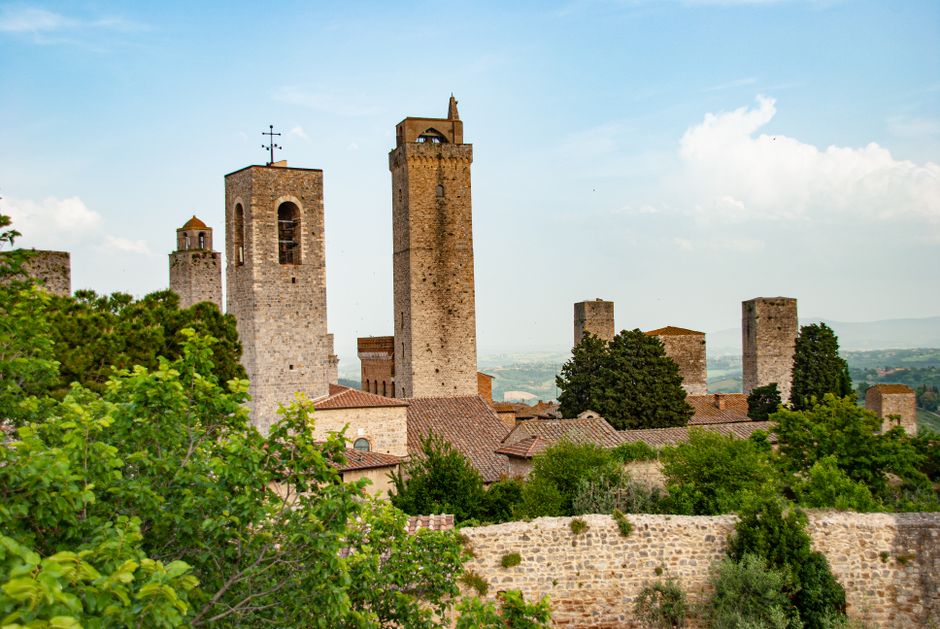 Stone medieval towers and walls of San Gimignano among green trees