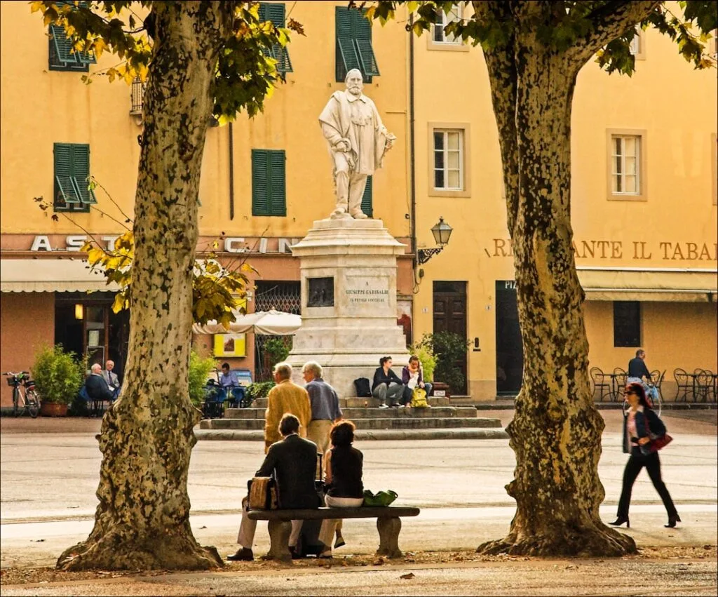 Lucca piazza with a statue framed by plane trees and benches