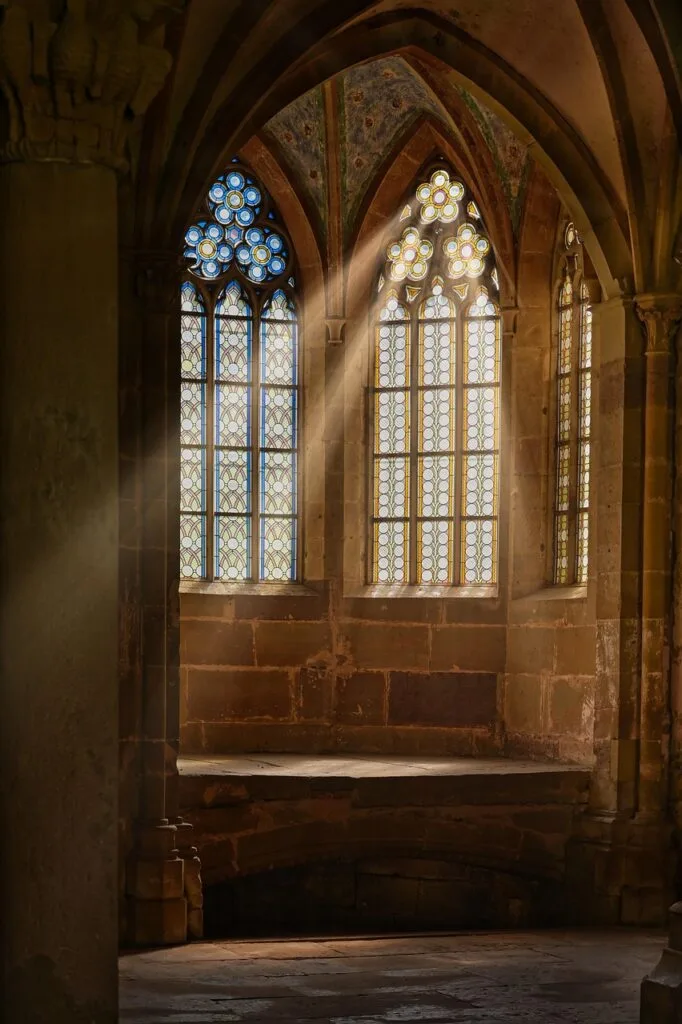 Gothic church interior in Lucca with tall stained-glass windows and sunbeams