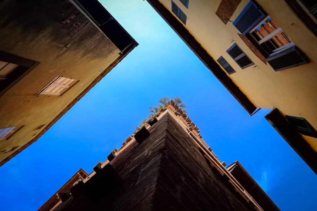 Looking up at narrow Lucca buildings framing a bright blue sky
