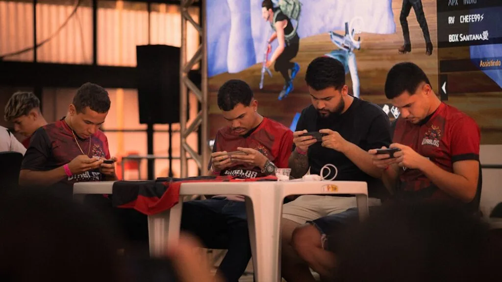 Four competitors at indoor mobile gaming tournament focused on phones