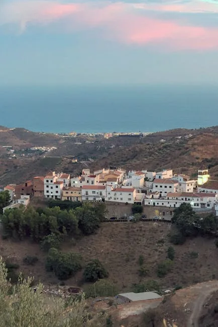 White hilltop village overlooking distant coastline under soft evening light