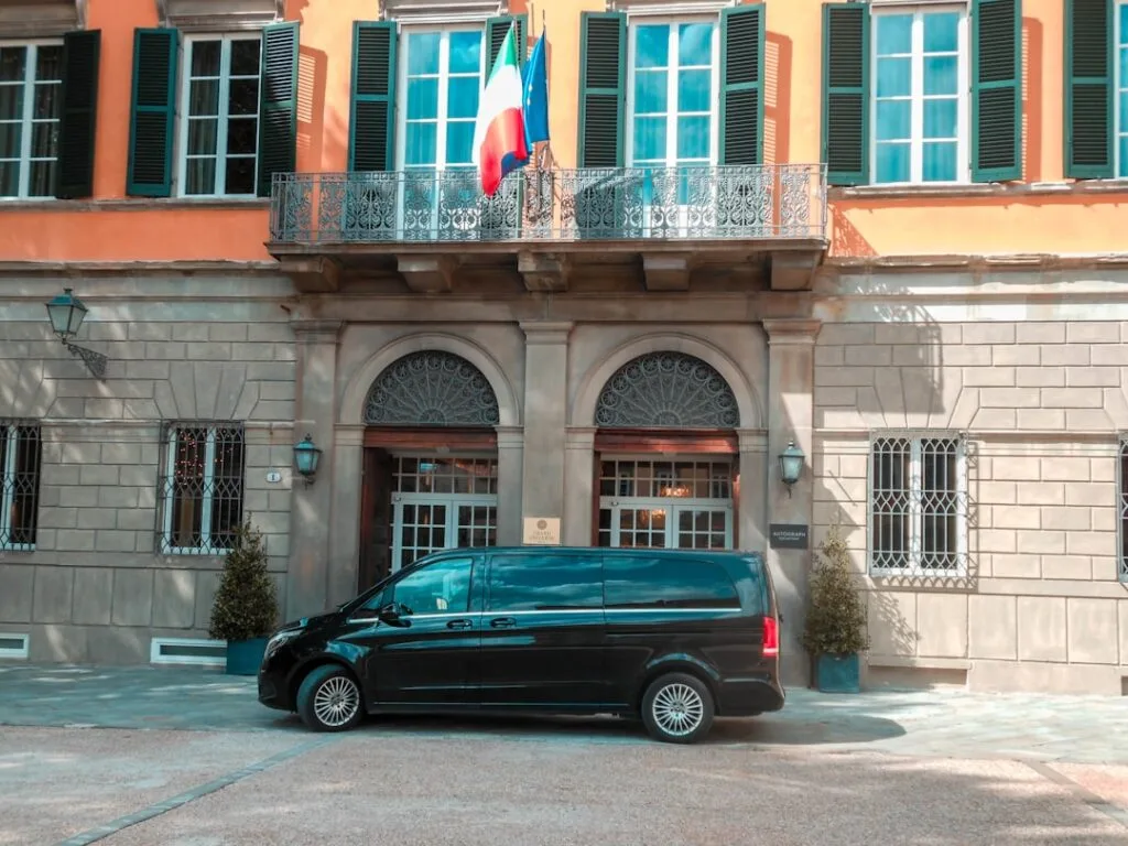 Black van parked outside an orange building with Italian flag in Lucca