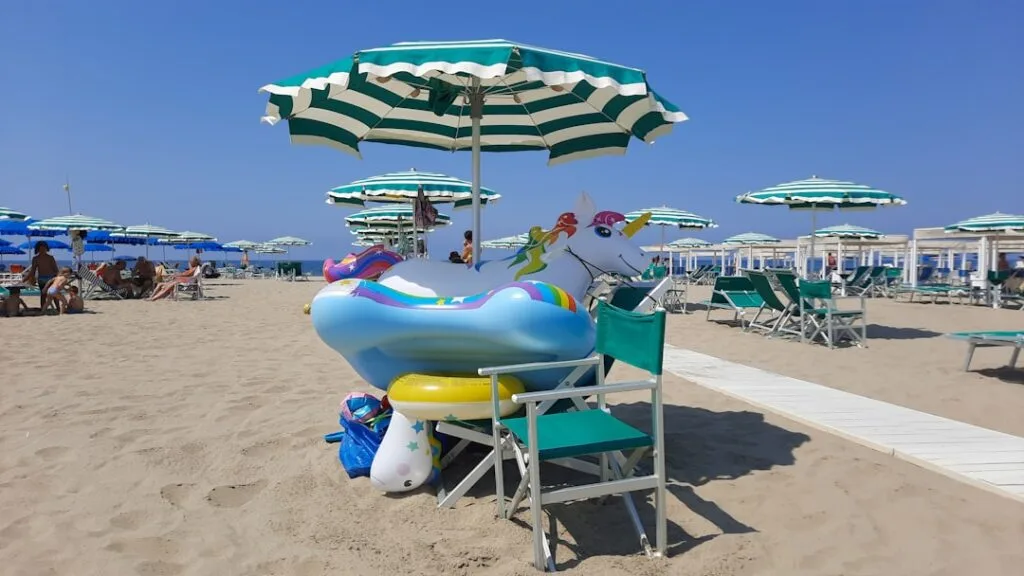 Inflatable unicorn float stacked under striped umbrellas on Versilia beach