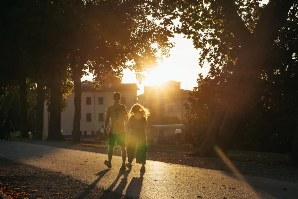 A couple walking along tree-lined path in Lucca at golden sunset