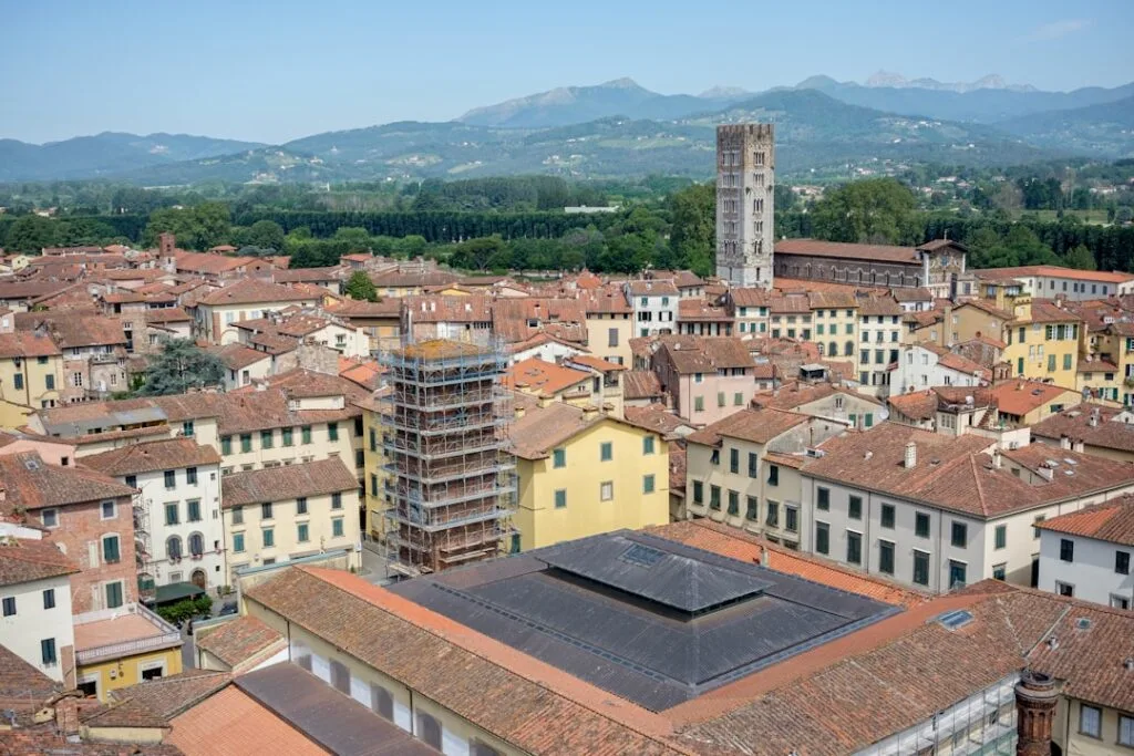 Aerial view of Lucca rooftops with medieval bell tower and distant hills