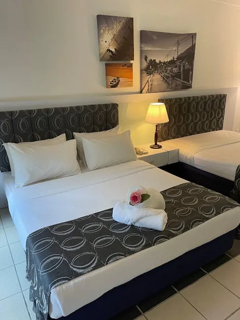 Two beds with white linens and towel rose in Lucca hotel room