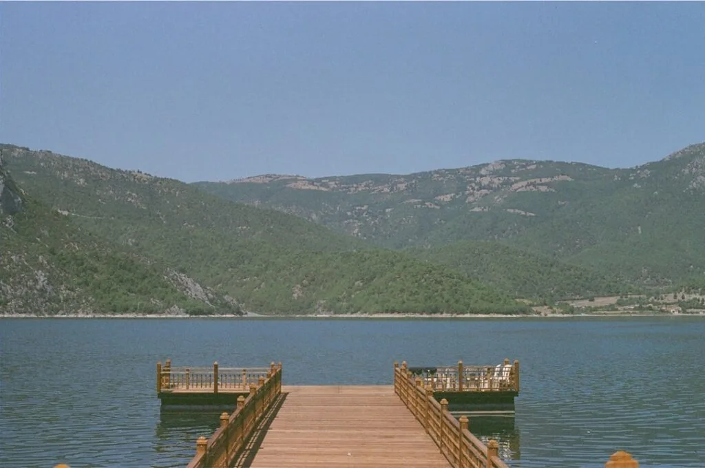 Wooden pier extending into a tranquil mountain lake in Garfagnana
