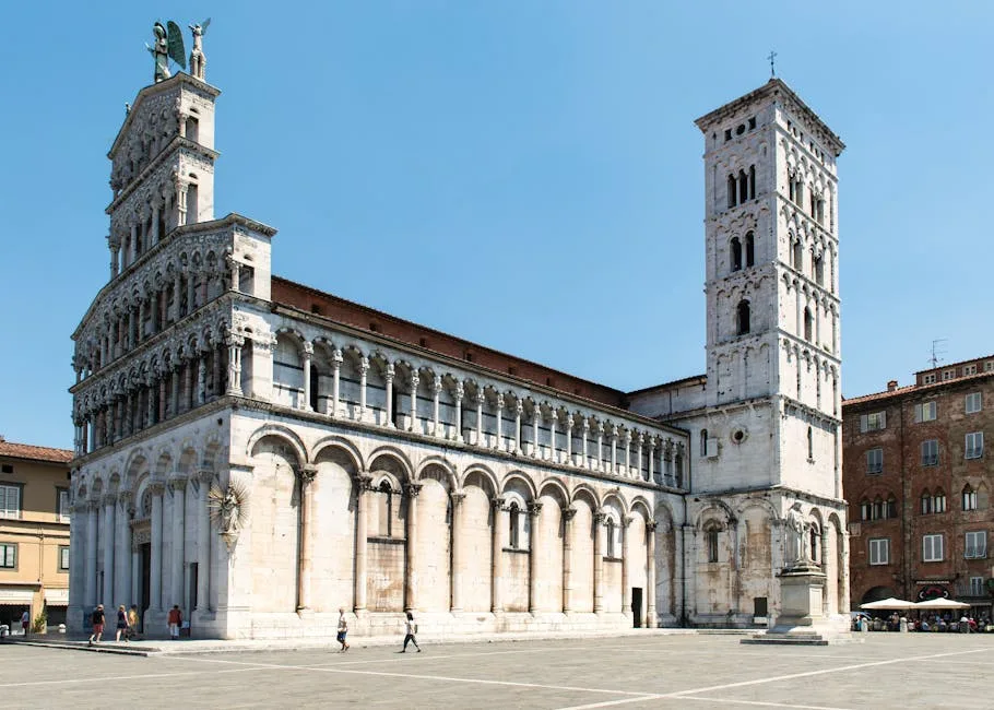 Sunlit Lucca cathedral with tall bell tower in spacious stone piazza
