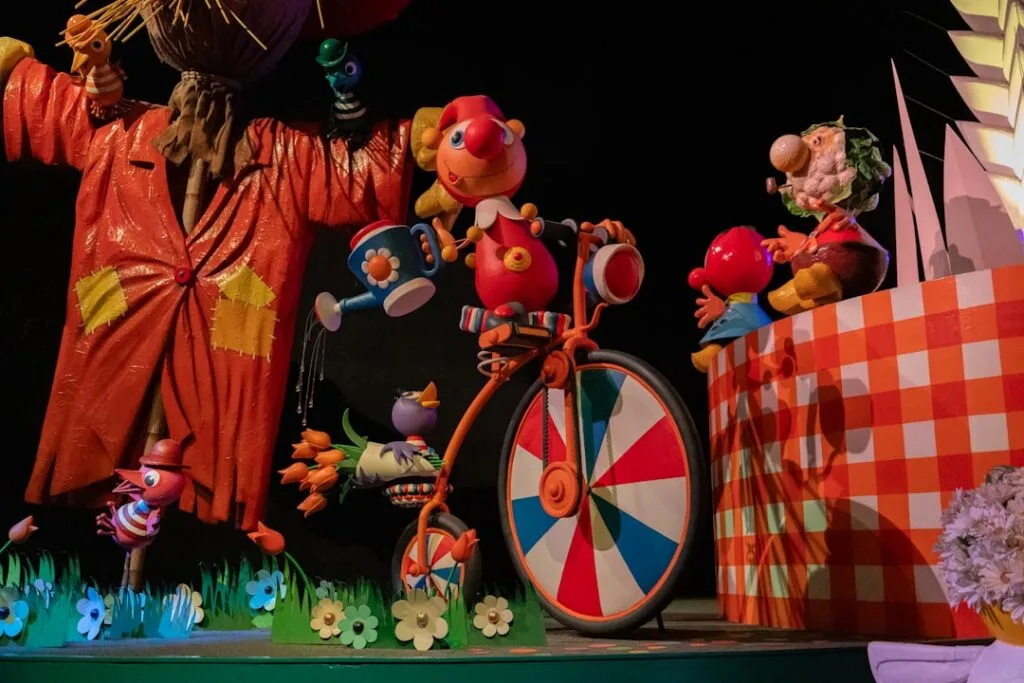 Colorful puppet characters and a toy bicycle on stage display