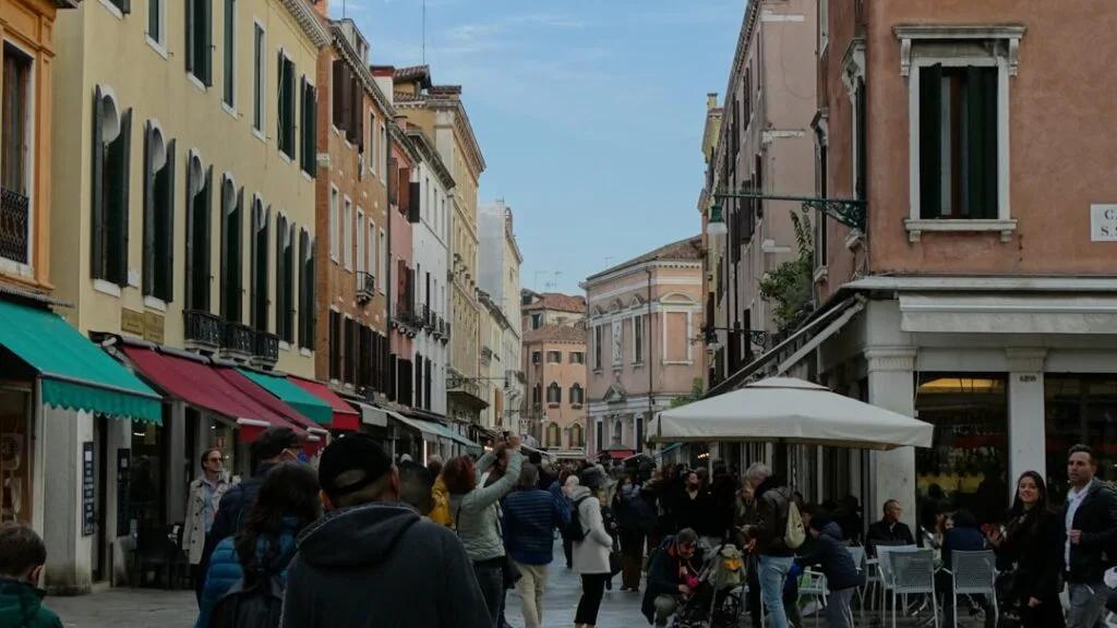 Busy pedestrian street with outdoor cafes and shoppers under awnings