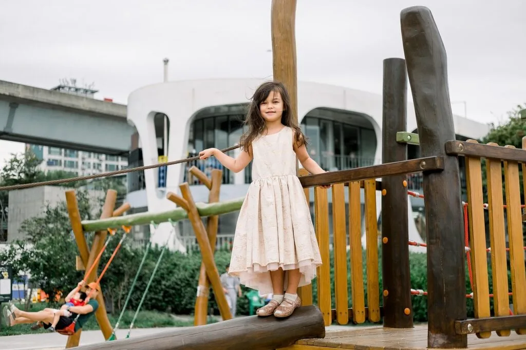 Young girl standing on wooden playground equipment in Lucca park