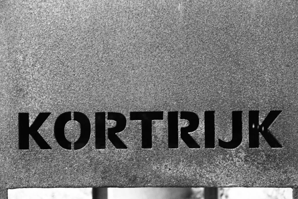 Mot 'KORTRIJK' découpé sur plaque métallique texturée grise