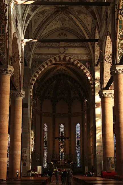 Interior nave of Lucca cathedral with towering columns and illuminated stained-glass