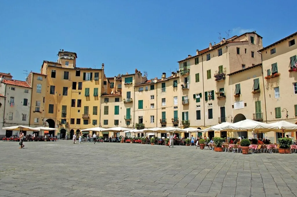 Curved yellow buildings and cafés at Lucca's Piazza dell'Anfiteatro