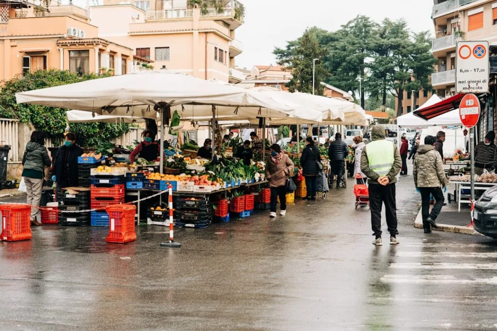 Rain-slick street with produce stalls and shoppers at a Lucca market