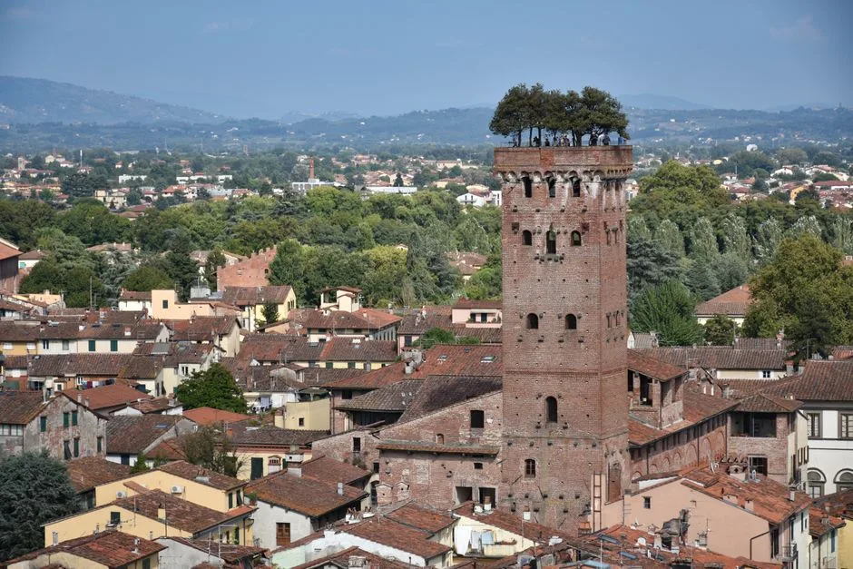 Torre Guinigi rising above Lucca rooftops with iconic oak trees
