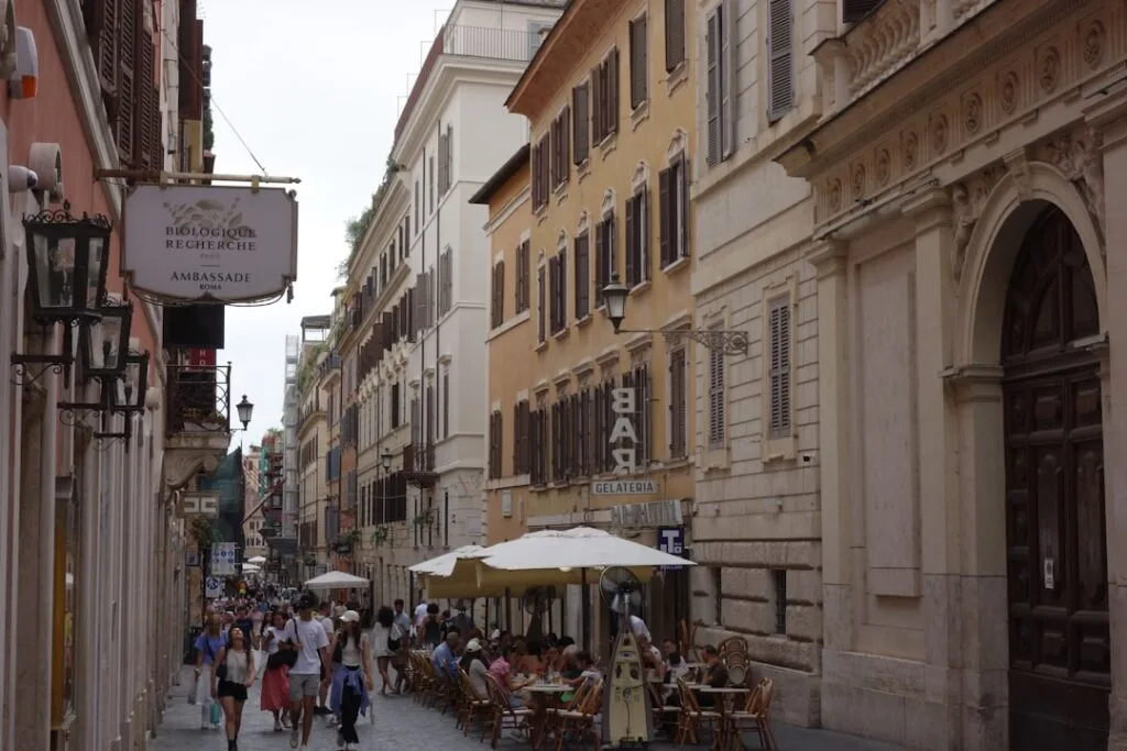 Crowded narrow street with outdoor cafés and shoppers in Lucca