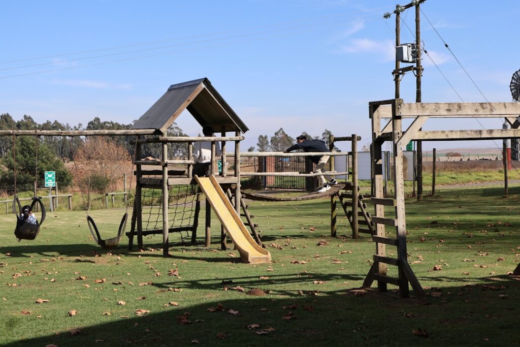 Wooden playground with slide and swings on a Tuscan farm lawn.