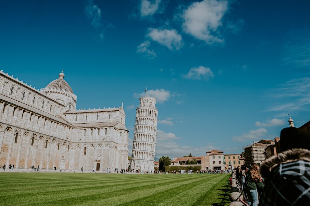 Leaning Tower of Pisa beside cathedral on expansive grassy piazza in Tuscany.