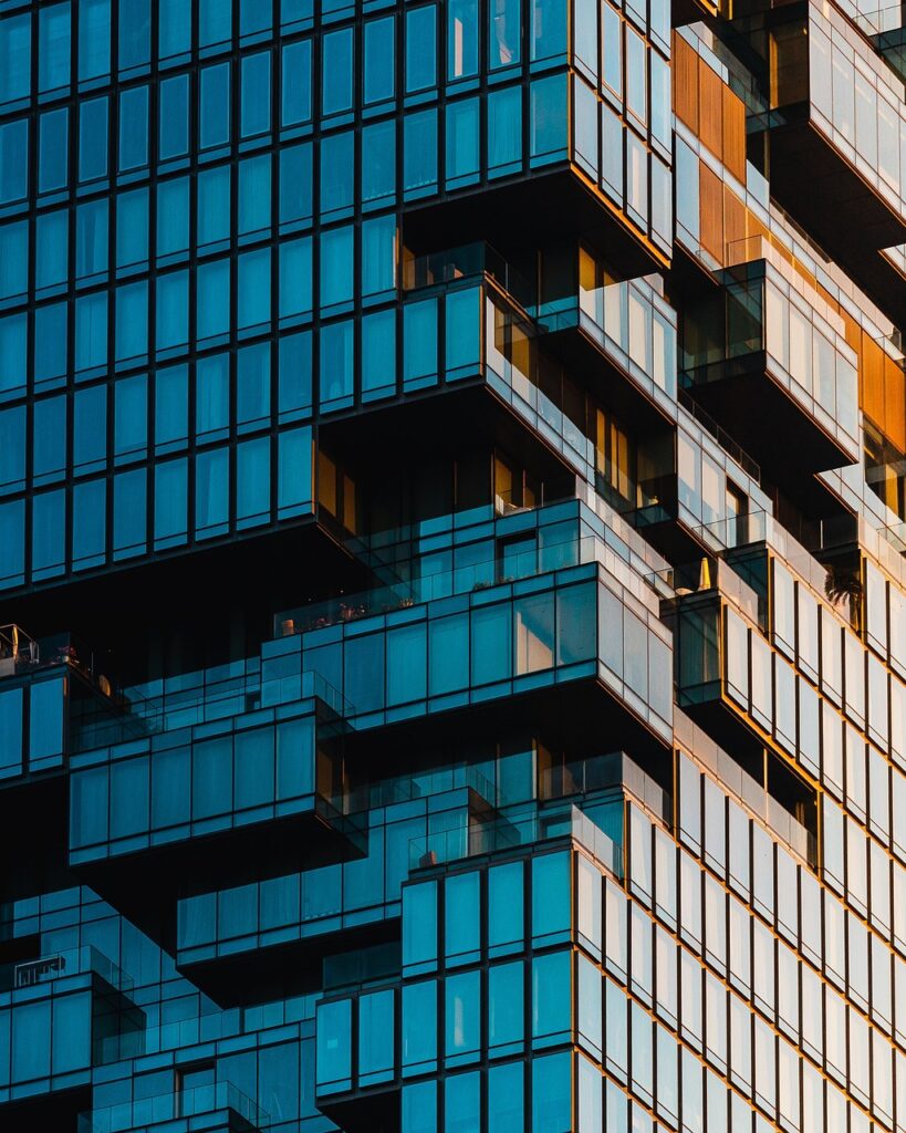 Modern glass building façade with staggered balconies and reflections