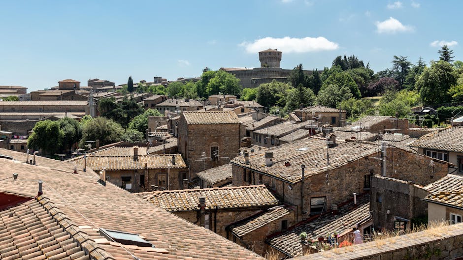 Terracotta daken en een forttoren in Toscane onder blauwe hemel