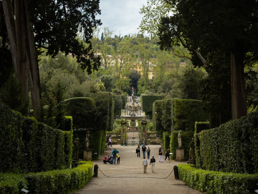 Formal Boboli Gardens allee with trimmed hedges, statues, and distant villa in Florence