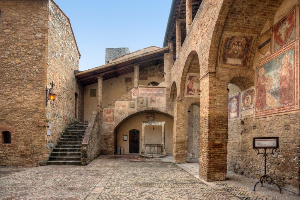 Cortile medievale con archi e affreschi nel centro di San Gimignano