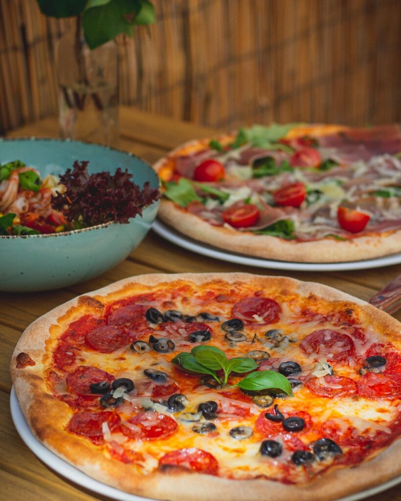 Pizze e insalata servite su tavolo rustico in Toscana