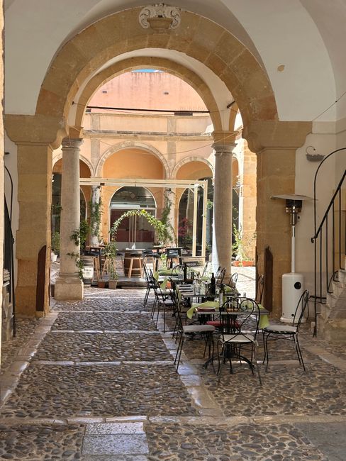 Sfeervolle binnenplaats met bogen, stenen vloer en terrasstoelen in Toscane