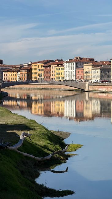 Kolorowe kamienice odbite w spokojnej rzece Arno w Toskanii