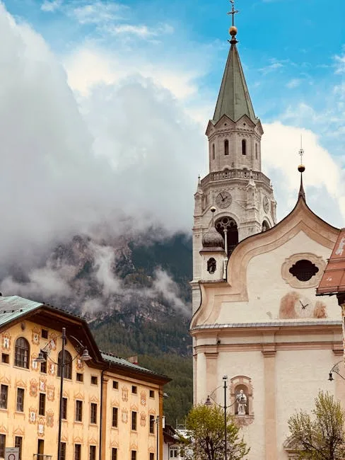 Clocher baroque et façades peintes devant les montagnes des Dolomites