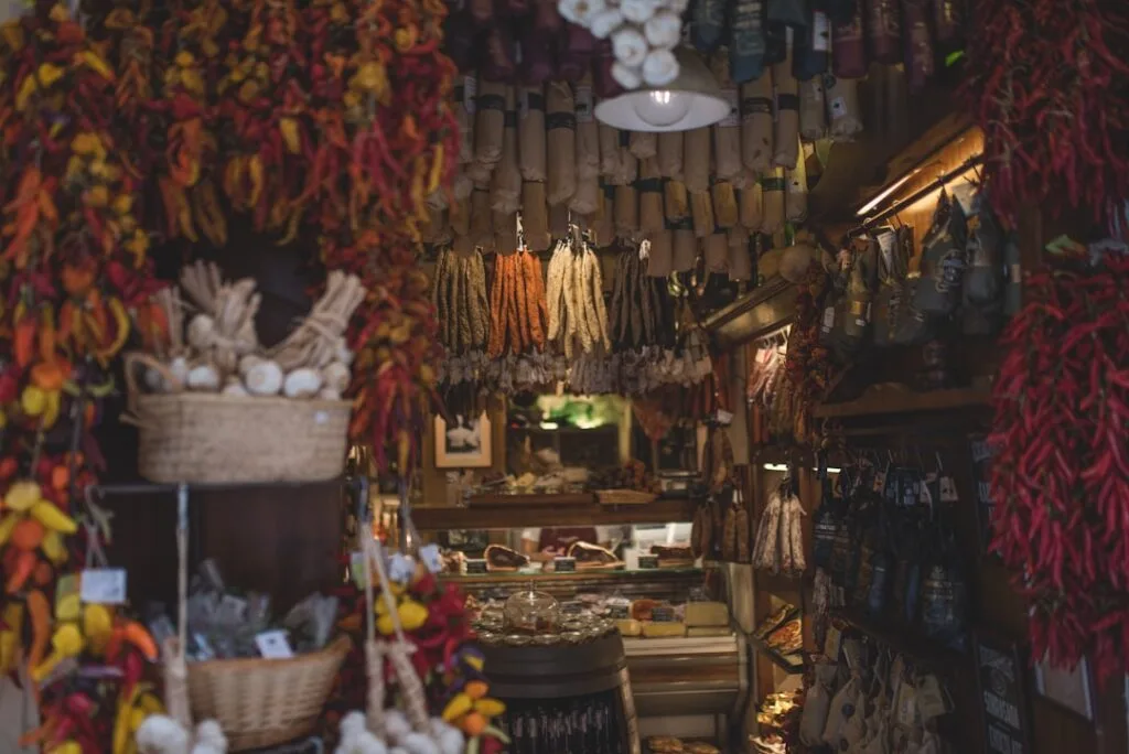 Étal d'épicerie avec saucissons et piments suspendus dans un marché des Dolomites