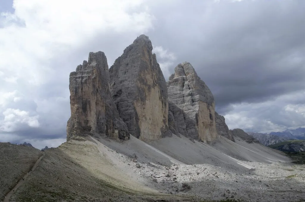 Trois imposantes tours rocheuses des Dolomites sous ciel orageux