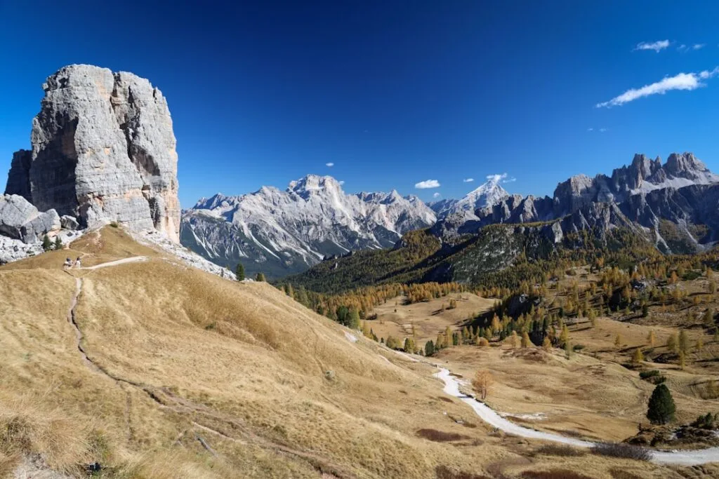 Sentier montant vers une haute tour de roche typique des Dolomites.
